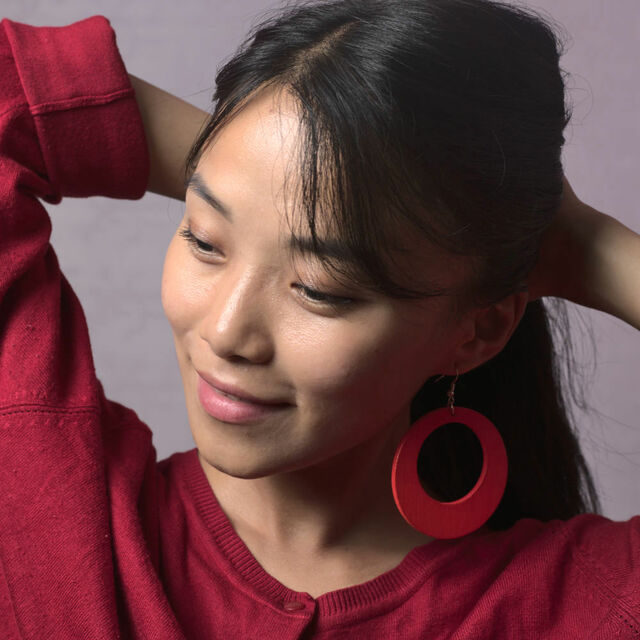 Model wearing a pair of red wooden earrings